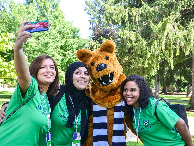 Three first-year students taking a selfie with the Nittany Lion